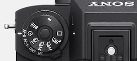 Product image highlighting the Drive Mode and Focus Mode dials on the camera top