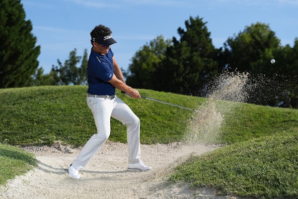 Example image of a golfer performing a bunker shot, moments after the club struck the ball